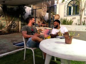 two men sitting in chairs at a table at Hostel das Canárias in Natal