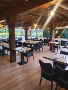 TrémeurにあるLes Dineux Villageのテーブルと椅子が備わるウッドフロアのレストランを併設しています。