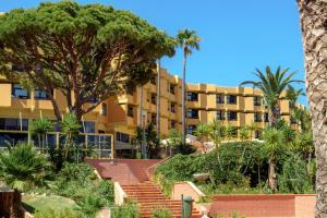 een groot geel gebouw met palmbomen en trappen bij Auramar Beach Resort in Albufeira