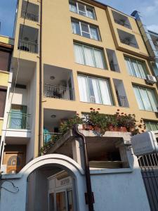 a tall yellow building with flowers in a balcony at Къща за гости WEST in Sunny Beach