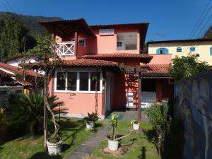 uma casa cor-de-rosa com plantas à frente. em Pousada Arrastão da Ilha em Abraão