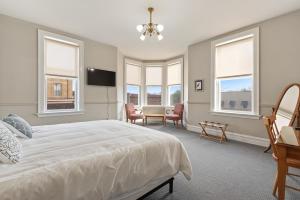 um quarto com uma grande cama branca e janelas em The Audubon Inn LLC em Mayville