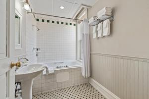 a white bathroom with a sink and a tub at The Audubon Inn LLC in Mayville