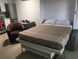 a bedroom with a bed and a chair and a table at K STREET CARRIAGE HOUSE Studio in Penticton