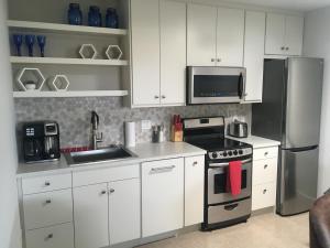 a kitchen with white cabinets and a stainless steel refrigerator at K STREET CARRIAGE HOUSE Studio in Penticton