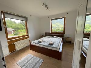 a bedroom with a bed and two windows at Haus Schwarzenbach in Weissbriach