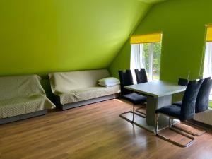 a green room with a table and chairs and a couch at Lauma in Kuldīga