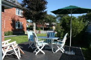 eine Terrasse mit einem Tisch, Stühlen und einem Sonnenschirm in der Unterkunft Haus Lene in Wyk auf Föhr