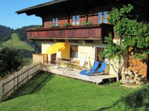 ein Haus mit 2 Stühlen, einem Tisch und einem Sonnenschirm in der Unterkunft Bio Bauernhof Brandgut in Mühlbach am Hochkönig