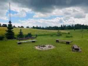 a park with benches and a fire in the grass at Svētgravas in Aklaisciems