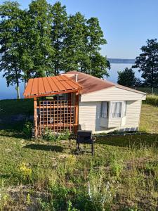 una pequeña casa con techo naranja en un campo en Domek letniskowy en Jeziorowskie