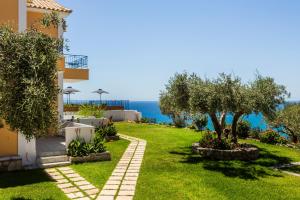 a garden in front of a house with a tree at Afrato Village Sea View apartments in Trapezaki