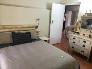 Schlafzimmer mit einem Bett, einer Kommode und einem Spiegel in der Unterkunft Boskloof Swemgat in Clanwilliam