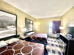 a hotel room with two beds and a flat screen tv at Super 8 by Wyndham Conway in Conway