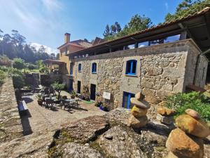 a stone house with a yard with tables and chairs at Quinta Estrada Romana - Albergue de Peregrinos in Cerdal