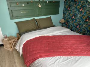 um quarto com uma cama com um cobertor vermelho em L’atelier du bonheur em Malandry