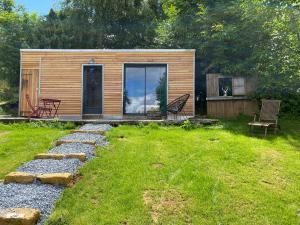 eine kleine Hütte mit einer Glastür im Hof in der Unterkunft L’atelier du bonheur in Malandry