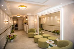 una sala de espera con sillas verdes, mesas y flores en Arletti Hotel en Ruse