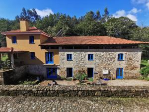 Casa de piedra grande con ventanas azules en un patio en Quinta Estrada Romana - Albergue de Peregrinos, en Cerdal