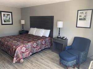 a hotel room with a bed and a blue chair at Executive Inn Locust Grove in Locust Grove