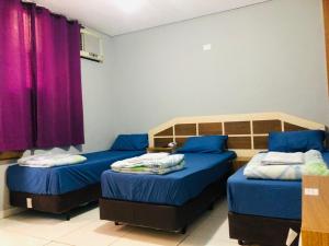 2 Betten in einem Zimmer mit lila Vorhängen in der Unterkunft Hotel Praça Orione in São Paulo