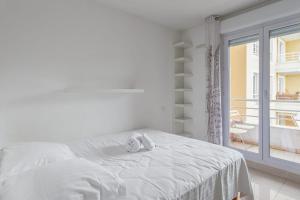 a white bedroom with a bed and a balcony at Appartement Californie - Welkeys in Nice