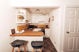 a kitchen with white cabinets and black stools at Princes Street Apartment in Perth