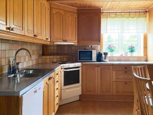 cocina con armarios de madera, fregadero y microondas en 8 person holiday home in VIRESTAD, en Virestad