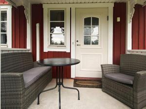 un porche con 2 sillas, una mesa y una puerta en 8 person holiday home in VIRESTAD, en Virestad