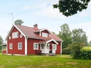 una casa roja con adornos blancos en un patio verde en 8 person holiday home in VIRESTAD, en Virestad