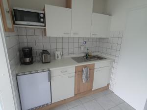 een keuken met witte kasten, een wastafel en een magnetron bij Ferienwohnung Preveza in Kappeln