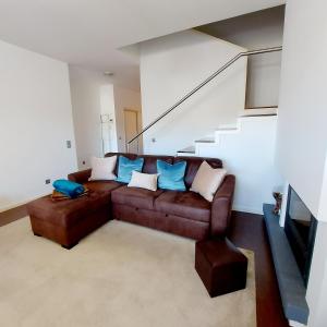 a living room with a brown leather couch with blue pillows at Casa De Luxo em Esposende in Esposende