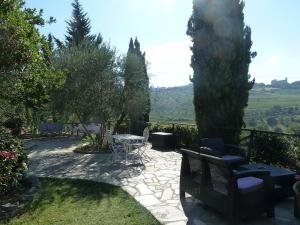 eine Terrasse mit einem Tisch und Stühlen im Garten in der Unterkunft Podere Palazzolo (ADULTS ONLY) in Castellina in Chianti