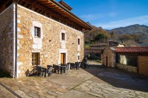 un edificio de piedra con mesas y sillas en un patio en EL PALACETE SOÑADO o, en La Roza