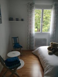 1 dormitorio con 1 cama, 1 silla y 1 ventana en La Roseraie, en Tonneins