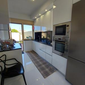 a kitchen with stainless steel appliances and a black chair at Casa De Luxo em Esposende in Esposende