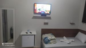 a living room with a couch and a tv on a wall at Pousada Quarto completo ar,wi fi e garagem gratuita in Aparecida