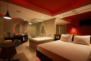a bedroom with a bed and a bathroom with a tub at Oásis Motel Piracicaba in Piracicaba