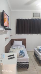 a room with a bed and a television in it at Pousada Quarto completo ar,wi fi e garagem gratuita in Aparecida