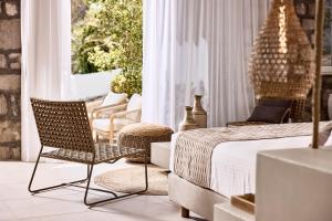 a bedroom with a bed and a chair next to a window at Nirome Luxury Suites in Adamantas
