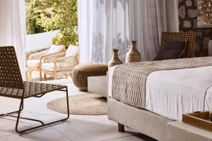 a bedroom with a bed and a chair on a balcony at Nirome Luxury Suites in Adamantas