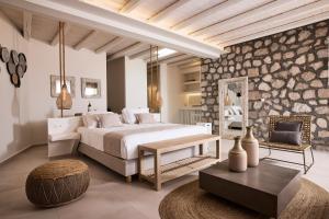 - une chambre avec un grand lit et un mur en pierre dans l'établissement Nirome Luxury Suites, à Adamas