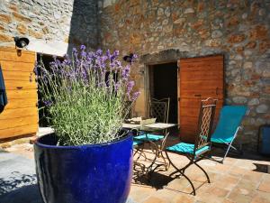 ヴァロン・ポン・ダルクにあるBastide du Barry - Centre historique de Vallon Pont d'arcの紫の花を用いた大きな青い鍋、テーブルと椅子