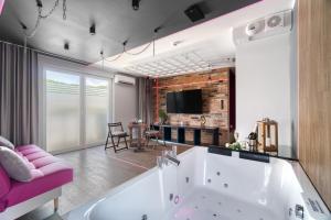 a large bathroom with a tub and a pink couch at Relaxroom Fuksja in Reda