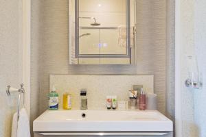 ein Badezimmer mit einem weißen Waschbecken und einem Spiegel in der Unterkunft Glenholmekendal in Kendal