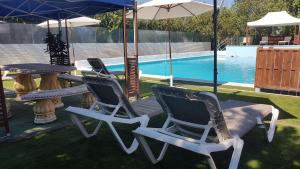 two chairs and a table with an umbrella next to a pool at Cortijo San José in Seville