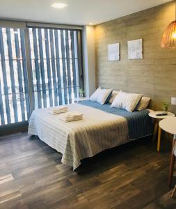 a bedroom with a large bed and large windows at Excelente Apartamento, a metros del Parque San Martín! in Mendoza