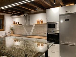 cocina con mesa de cristal y microondas en Casa Rural Nogalia, en Villanueva de los Nabos