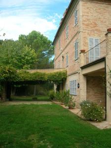 a large brick building with a grass yard at Villa lussuosa con piscina e giardino 350m2 in Montottone