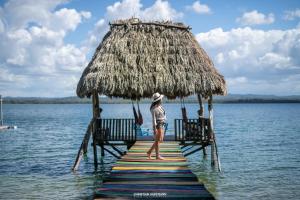 a person standing on a dock in the water at Hotel Gringo Perdido in El Remate